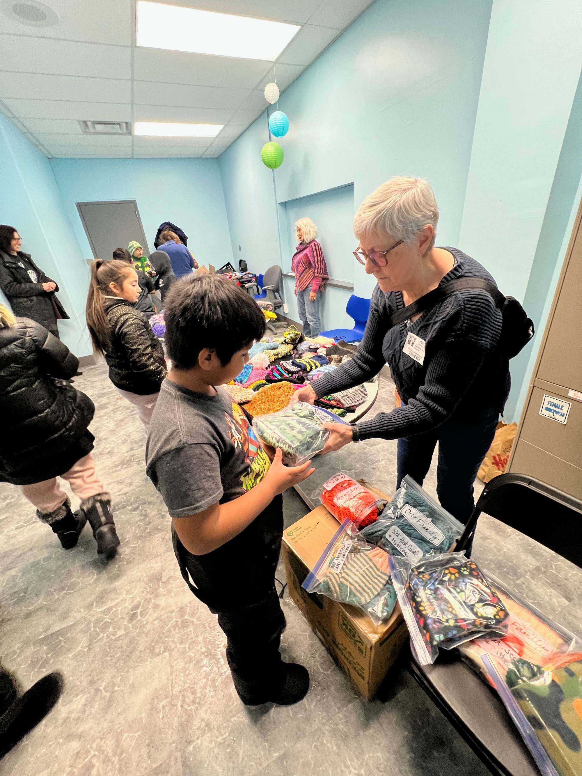 One of the knitters handing a student an item.